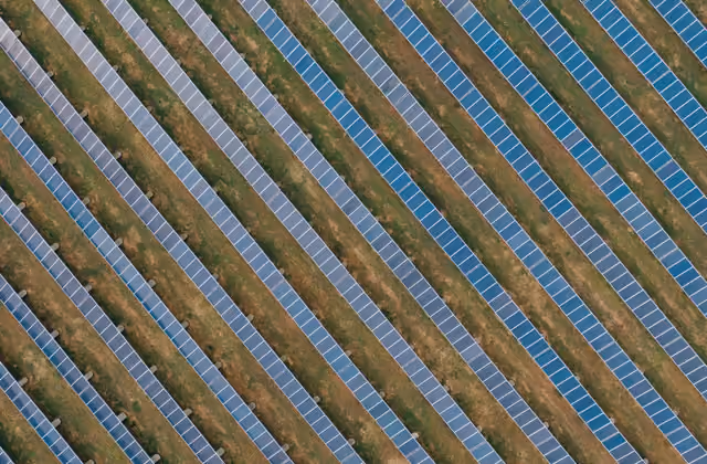File di pannelli fotovoltaici a terra viste dall'alto: la potenza in kW che decide il costo dell'impianto.