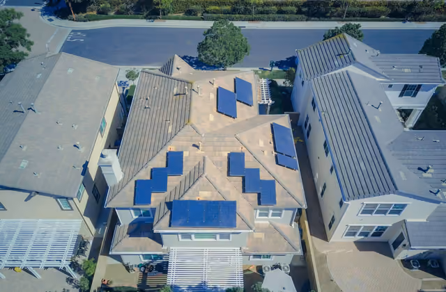 Villetta vista dall'alto con pannelli fotovoltaici su più falde del tetto, in un quartiere residenziale.